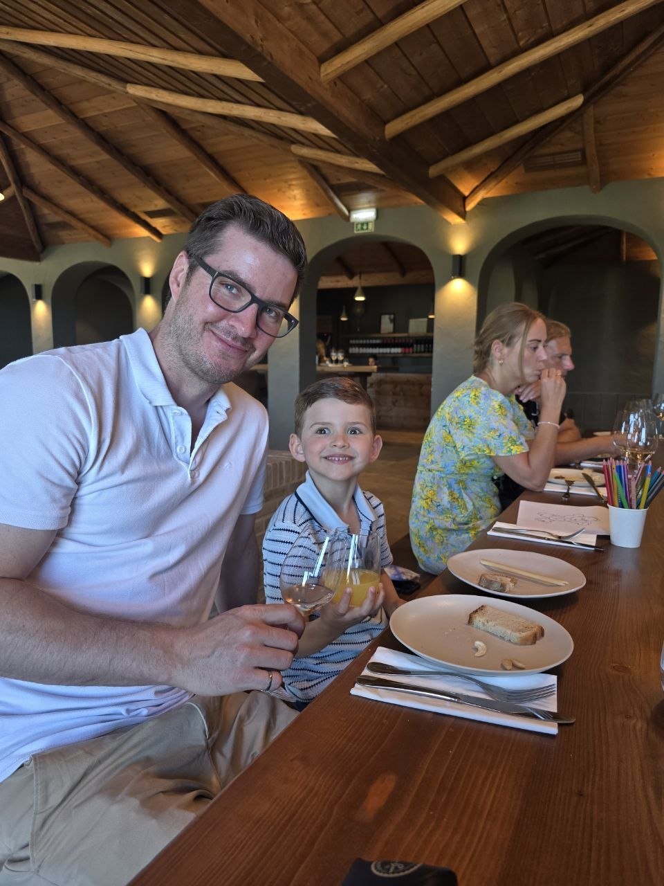 Ben and Noah smiling at the Cabrita Wines tasting table with wine and orange juice