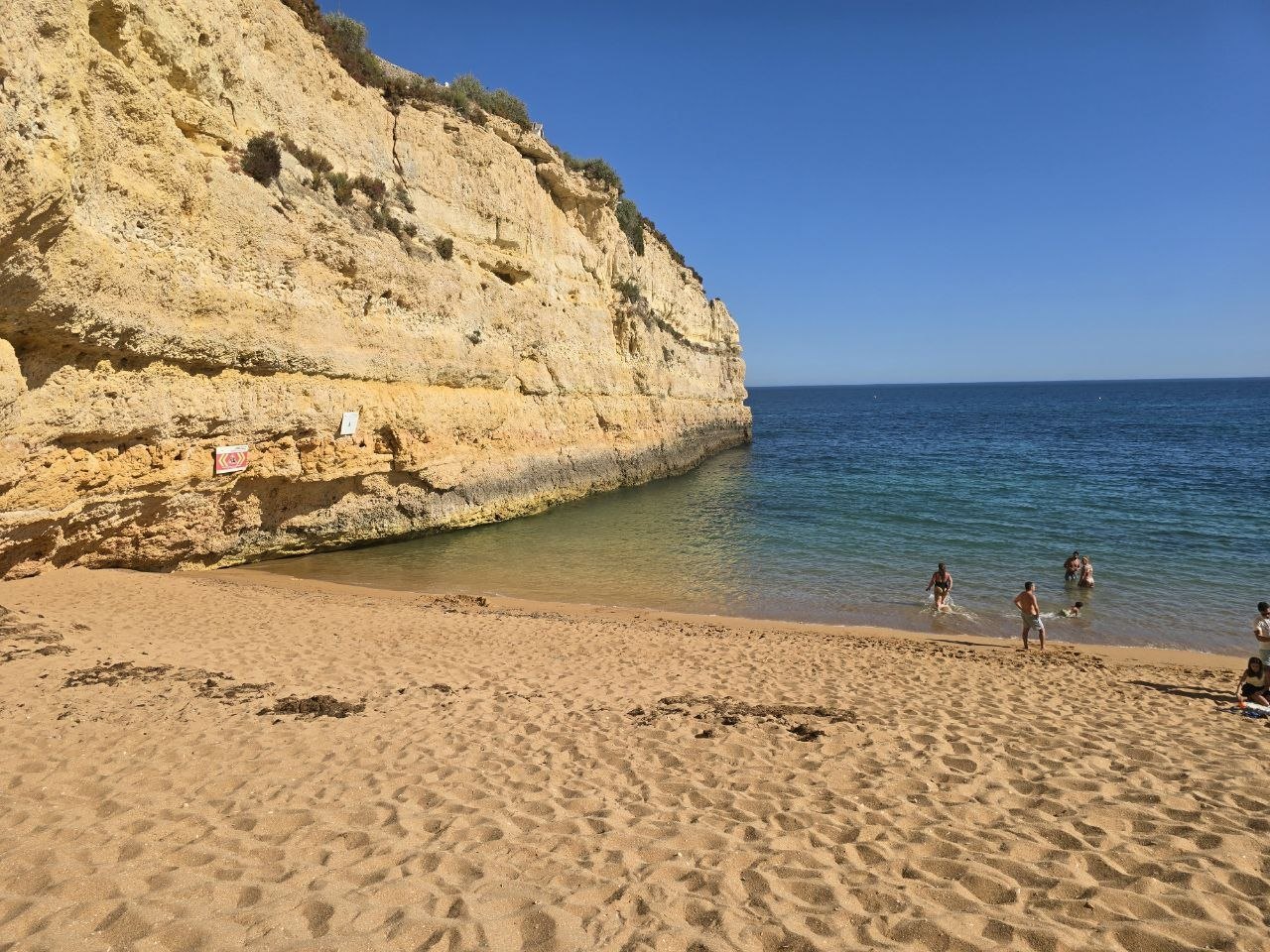 Wide view of Praia de Nossa Senhora da Rocha cove below golden limestone cliffs