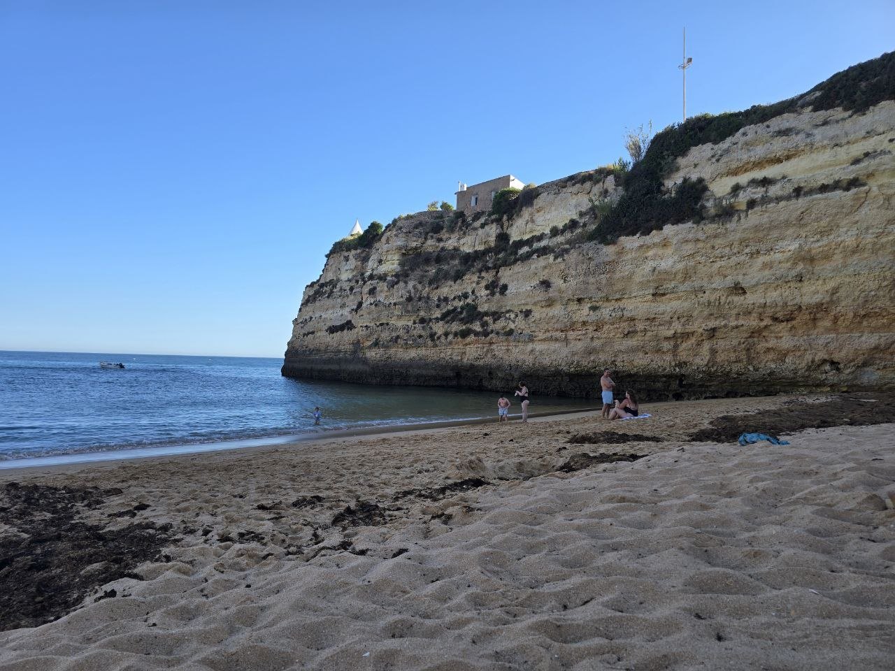 Quiet end of Praia de Nossa Senhora da Rocha beneath the chapel cliff and calm blue water