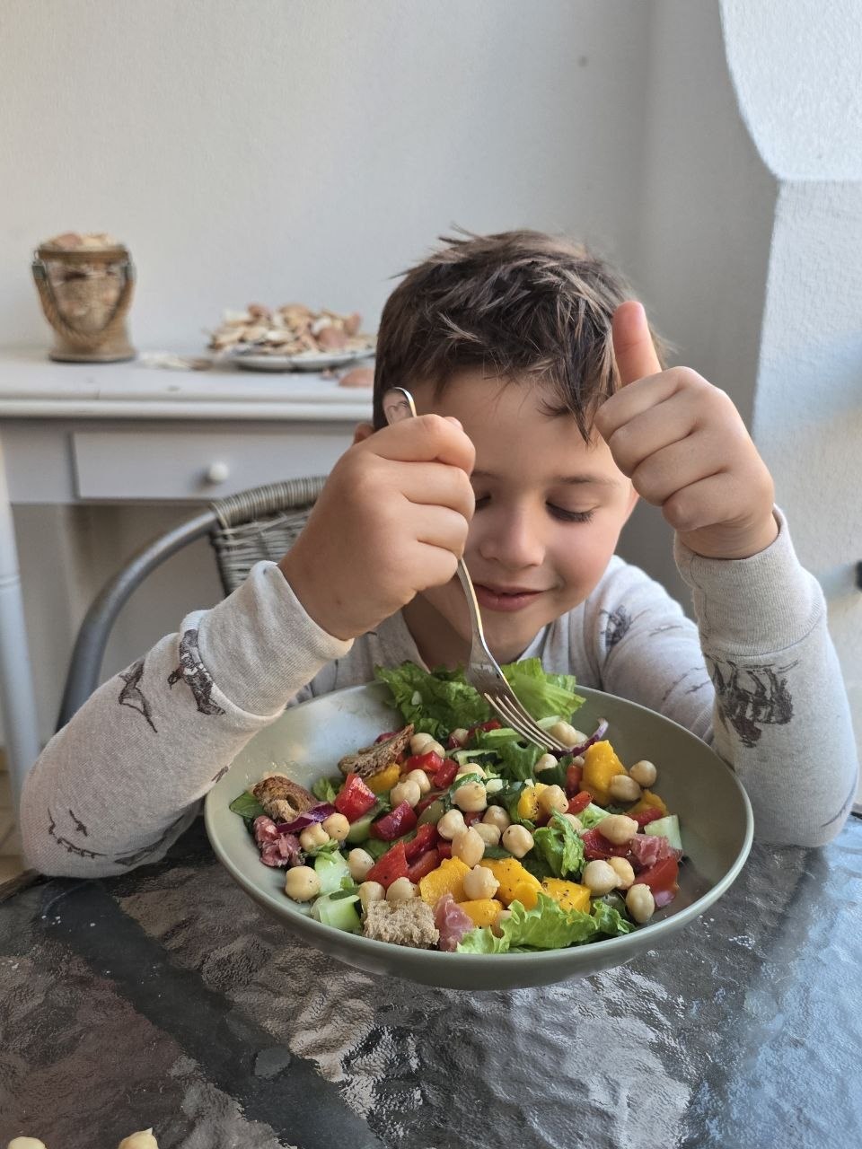 Noah smiling and giving a thumbs-up beside a colourful salad bowl at the Carvoeiro condo