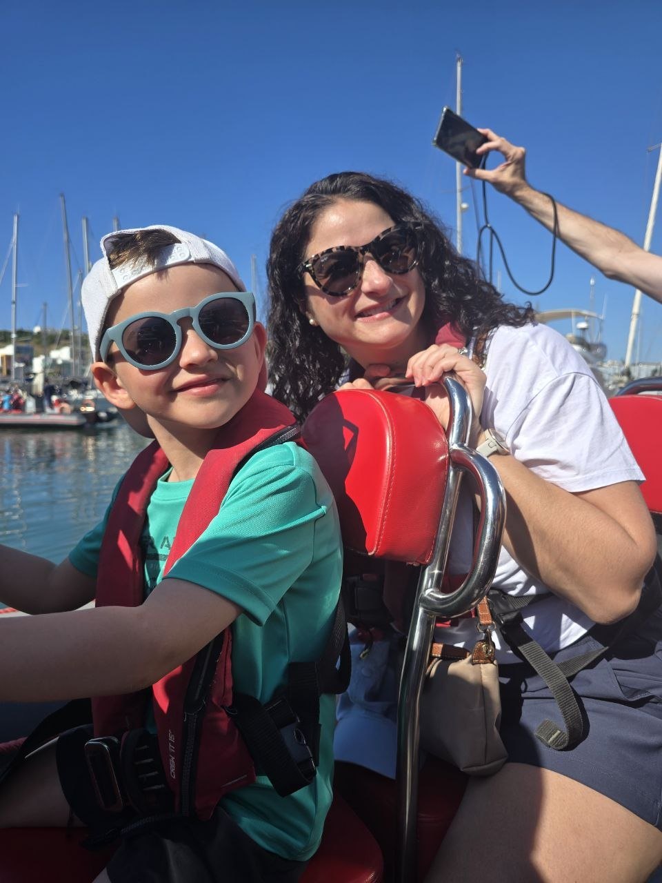Noah and Catherine sitting on the zodiac boat at the marina in bright sun