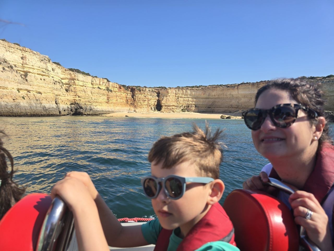 Noah and Catherine on the zodiac with golden Algarve cliffs and turquoise water behind them