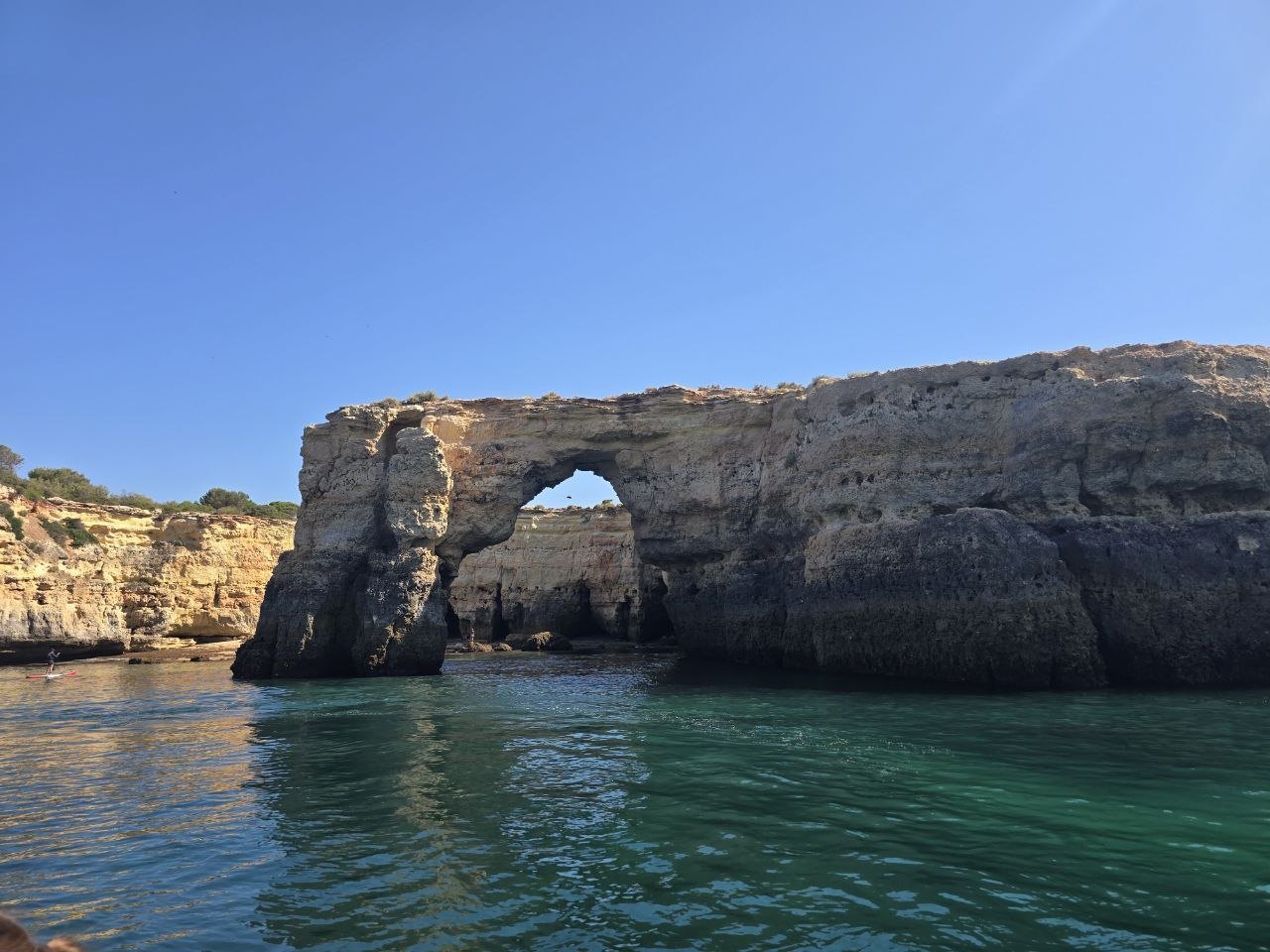 A natural rock arch in the Algarve cliffs seen from the water