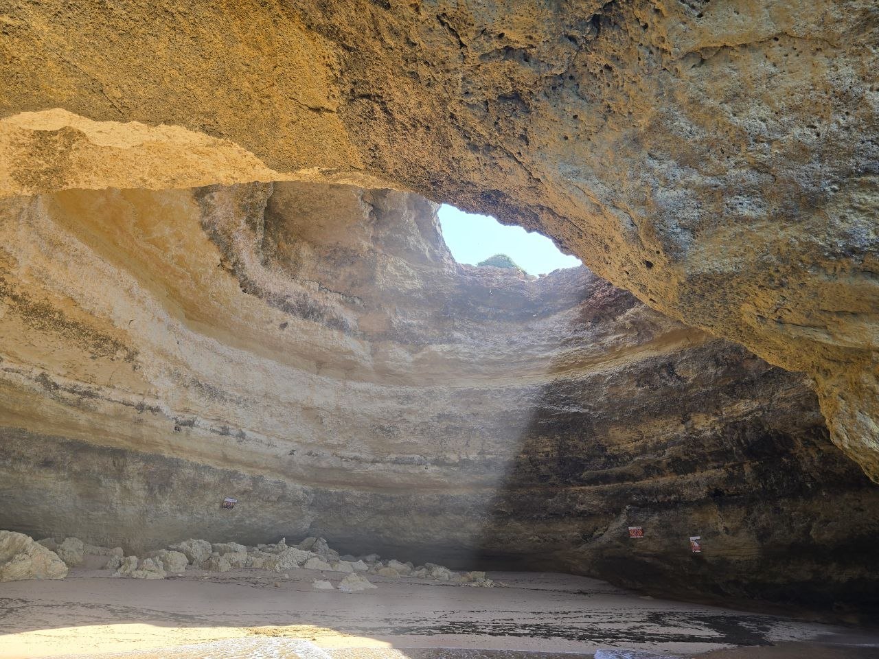 Inside Benagil Cave looking up at the circular skylight in the rock ceiling