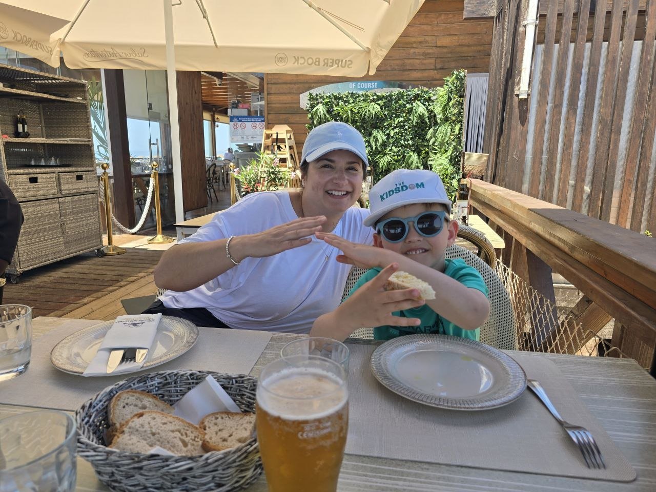 Catherine and Noah smiling at an outdoor beach restaurant table with bread and drinks