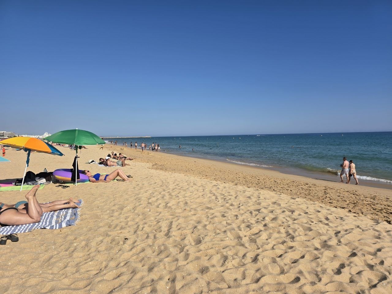 Long sandy shoreline with umbrellas, beachgoers, and calm blue Atlantic water