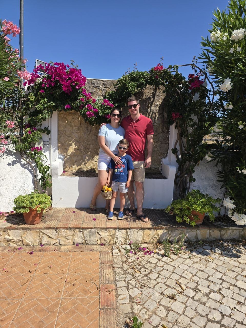 Family photo in a sunny Quinta de Santo Estevão courtyard with flowers and a basket of oranges
