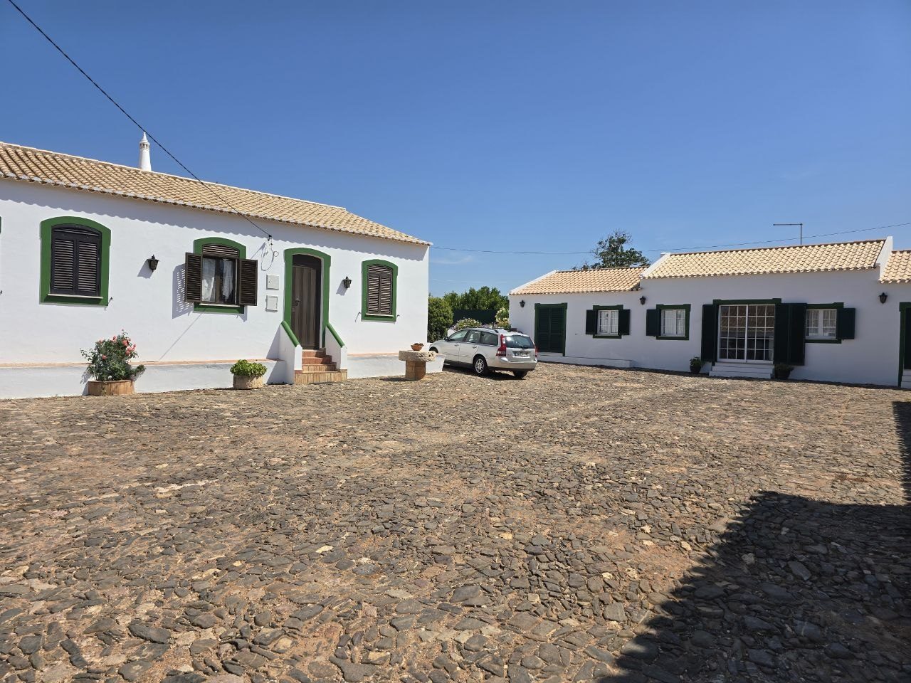 White farm buildings with green shutters and a cobblestone courtyard at Quinta de Santo Estevão