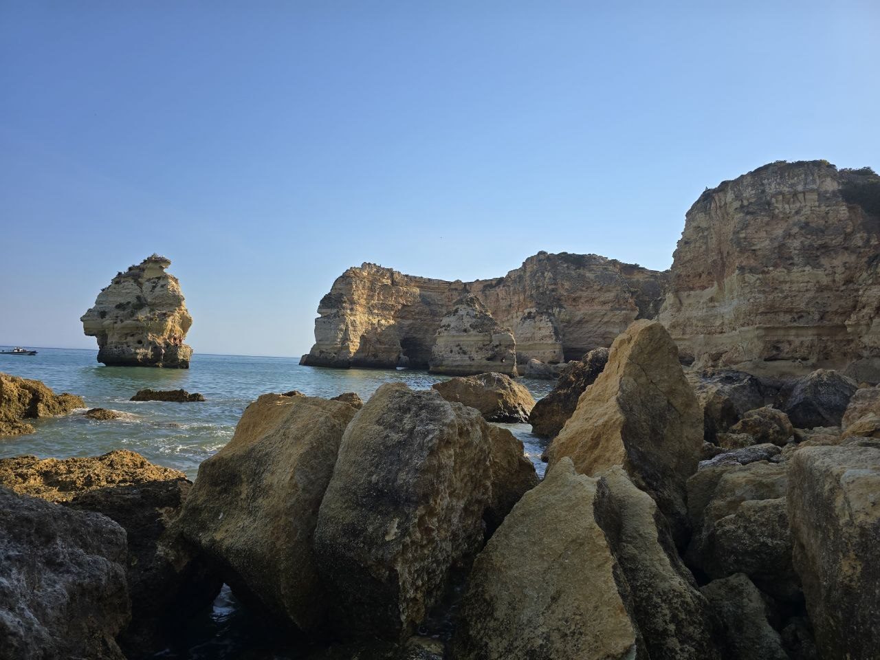 Rocky approach along Praia da Marinha with golden cliffs and sea stacks ahead