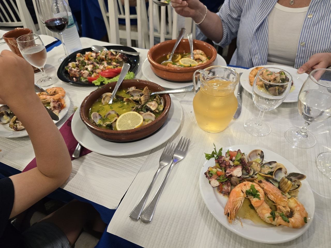 Seafood dinner table with clams, shrimp, octopus salad, and wine on the final night in Lisbon