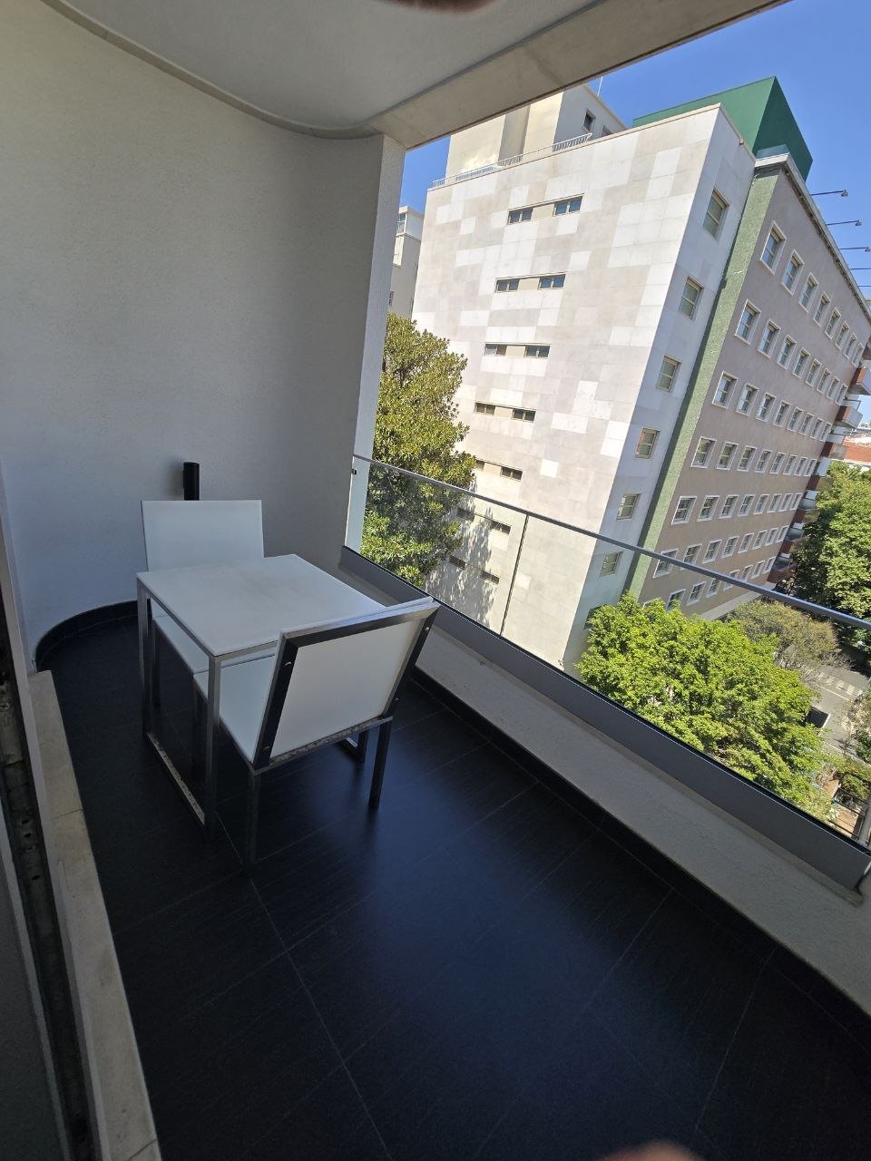 Small balcony at the final Lisbon hotel looking toward nearby buildings and trees