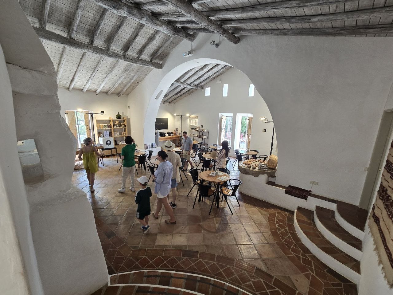 Rustic Monterosa tasting room with white arches, wood ceiling beams, round tables, and visitors