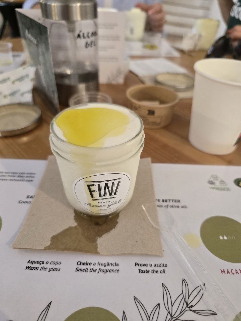 Cup of vanilla gelato topped with golden olive oil on a Monterosa tasting mat