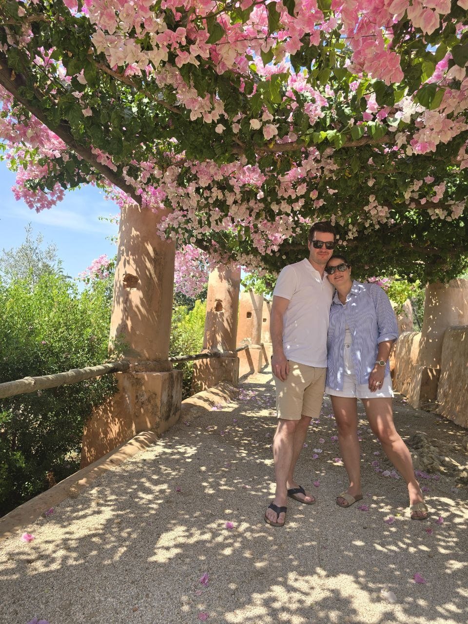 Ben and Catherine standing together beneath pink bougainvillea flowers at Monterosa