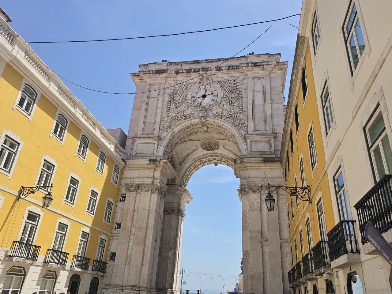 Close upward view of the Arco da Rua Augusta between yellow Lisbon buildings