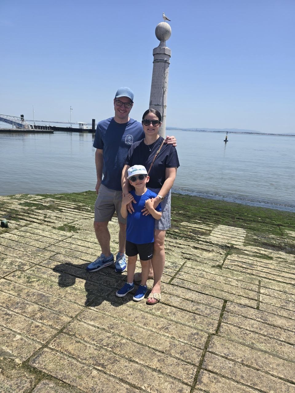 Family standing by the river at Cais das Colunas in Lisbon