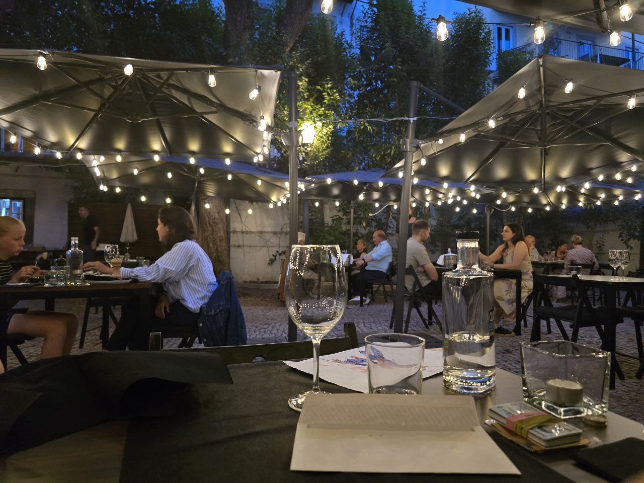 Clube de Jornalistas garden patio at dusk with umbrellas and warm string lights