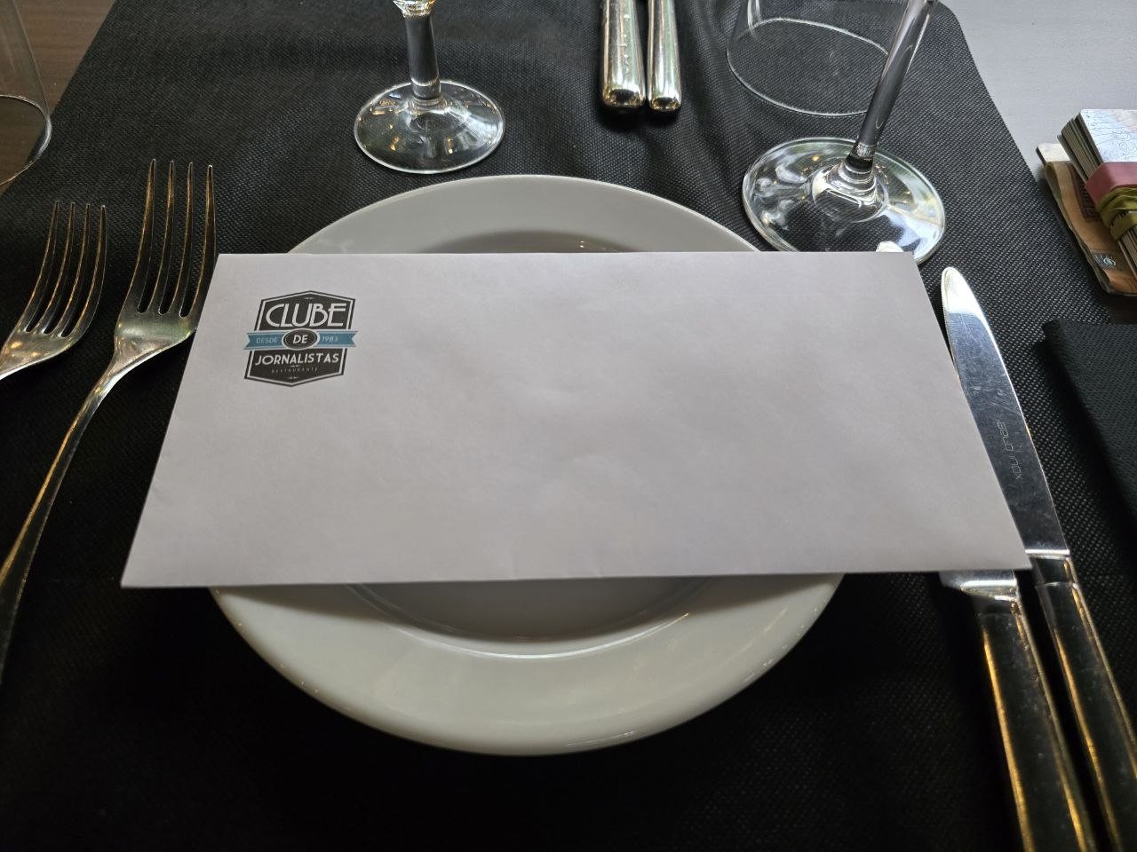 Clube de Jornalistas folded menu on a place setting with glasses and cutlery