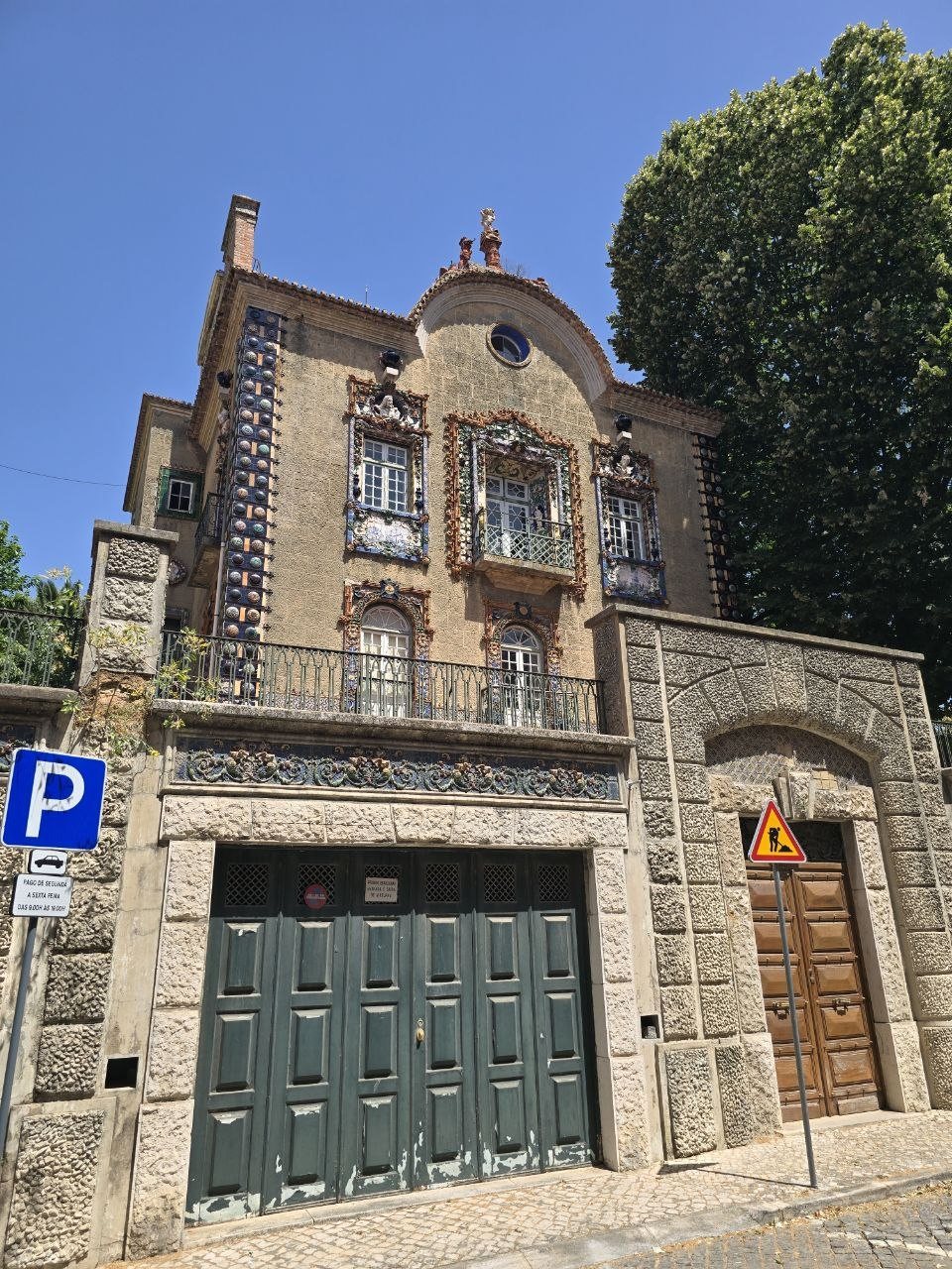 Ornate Lisbon house with colorful ceramic tile details, stonework, and a green garage door