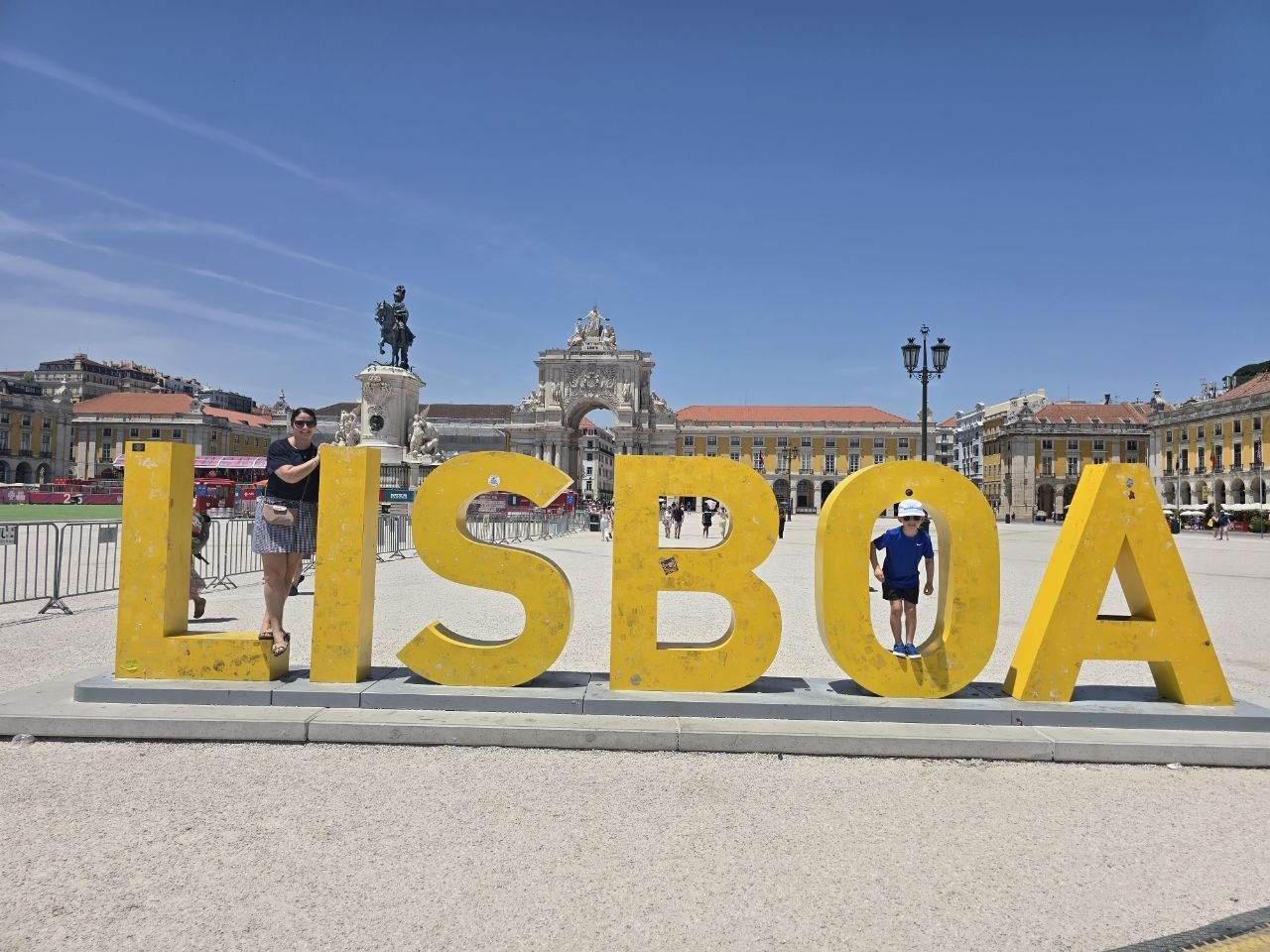Catherine and Noah posing with the giant yellow LISBOA letters in Praça do Comércio