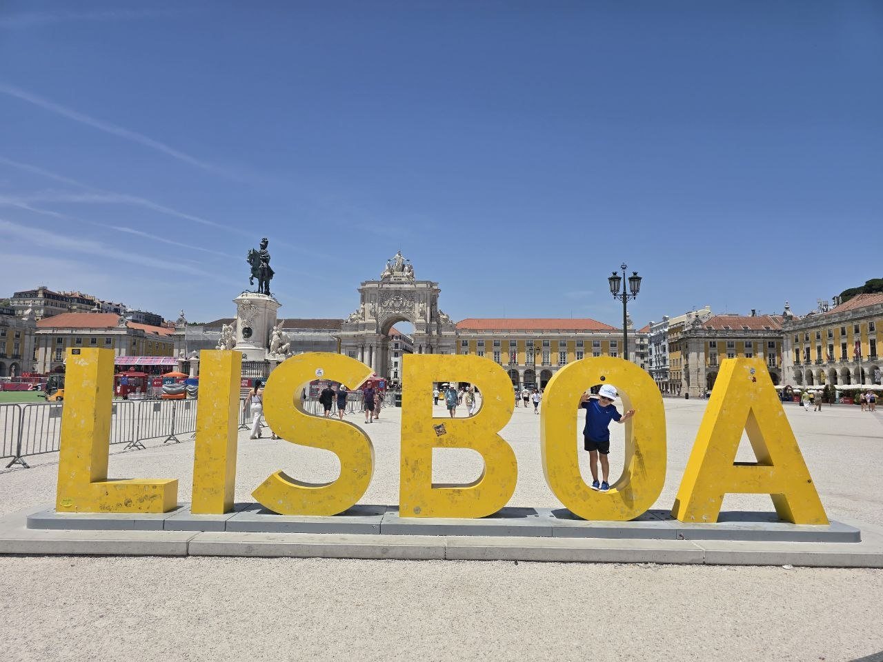 Noah posing inside the giant yellow LISBOA letters at Praça do Comércio