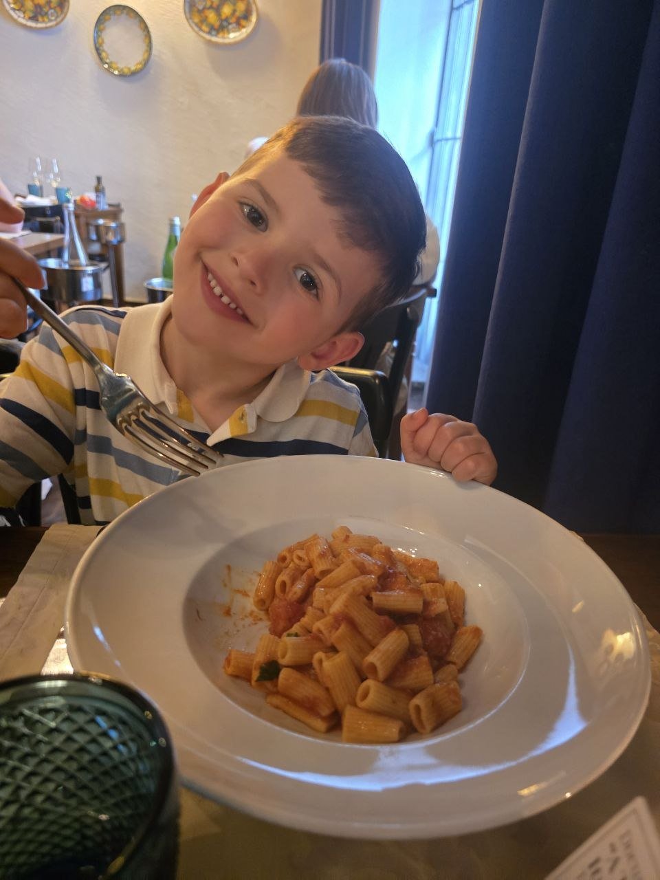 Noah smiling with a plate of tomato pasta at Come Prima
