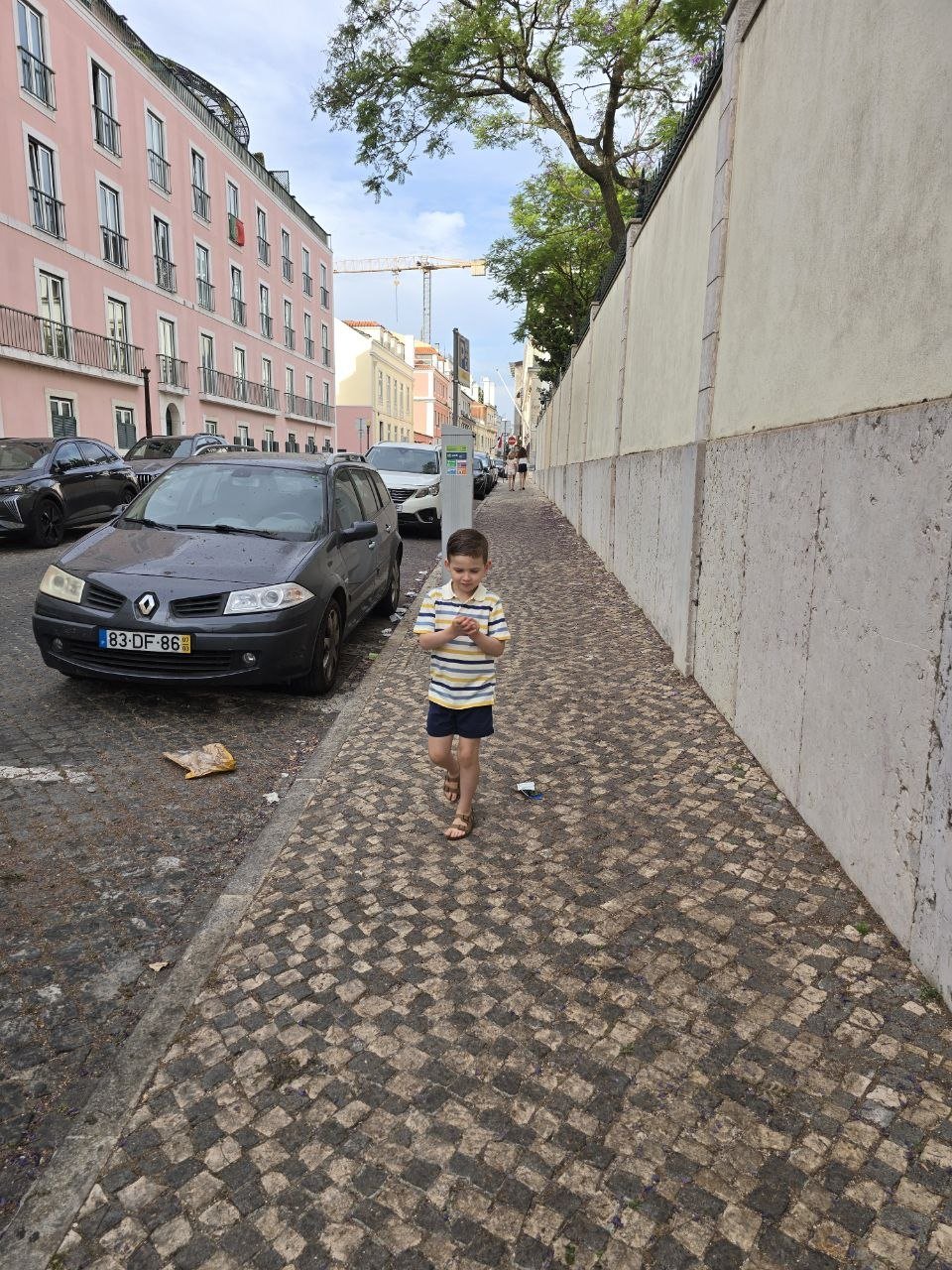 Noah walking along a Lisbon cobblestone sidewalk on the way to Come Prima