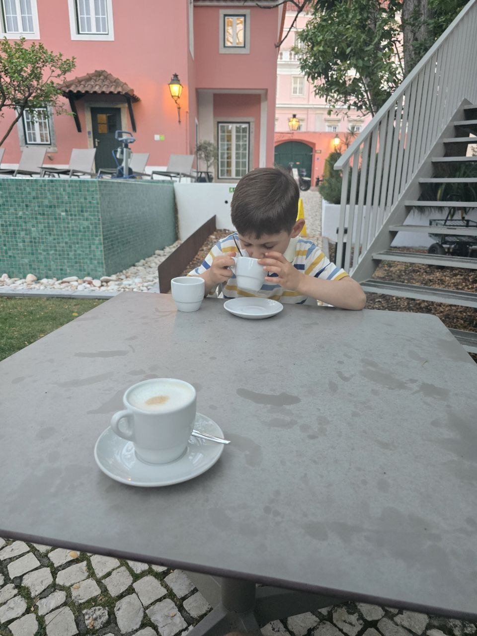 Noah sipping tea at an outdoor Jardim da Lapa poolside table in the evening