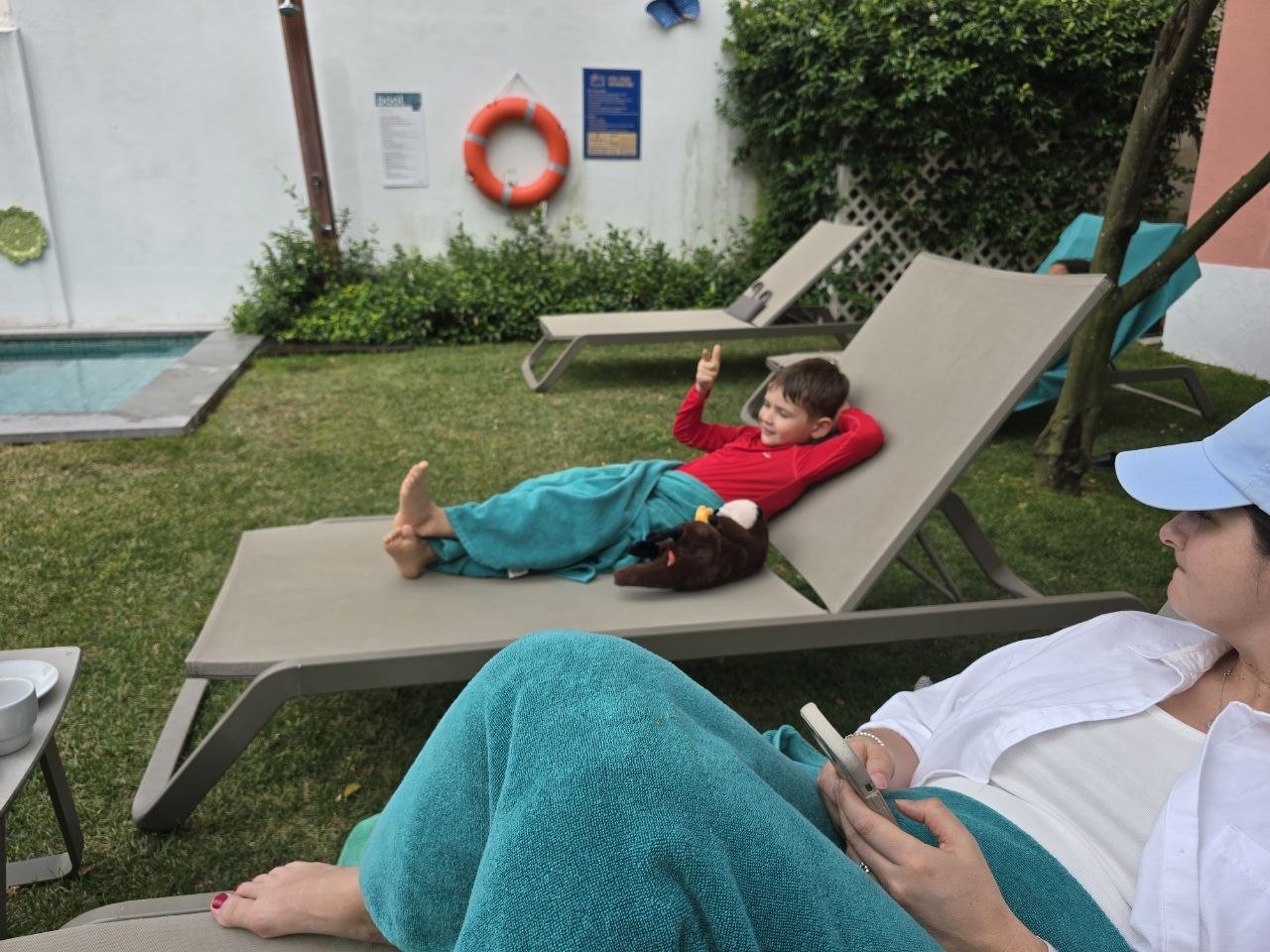 Noah wrapped in a towel on a Jardim da Lapa pool lounger with Catherine nearby