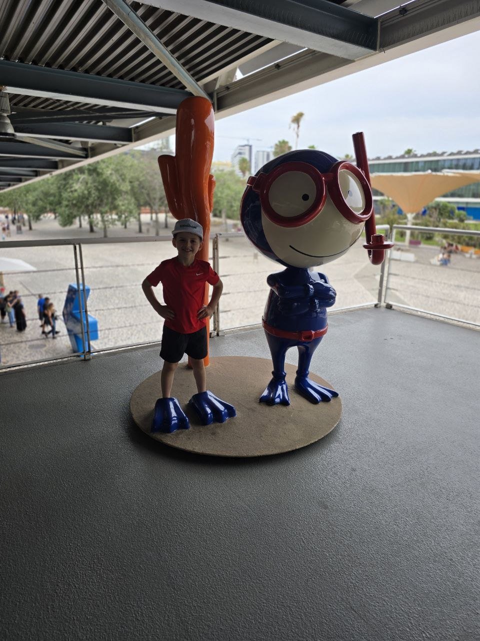 Noah standing beside a snorkel mascot statue and wearing oversized blue flippers