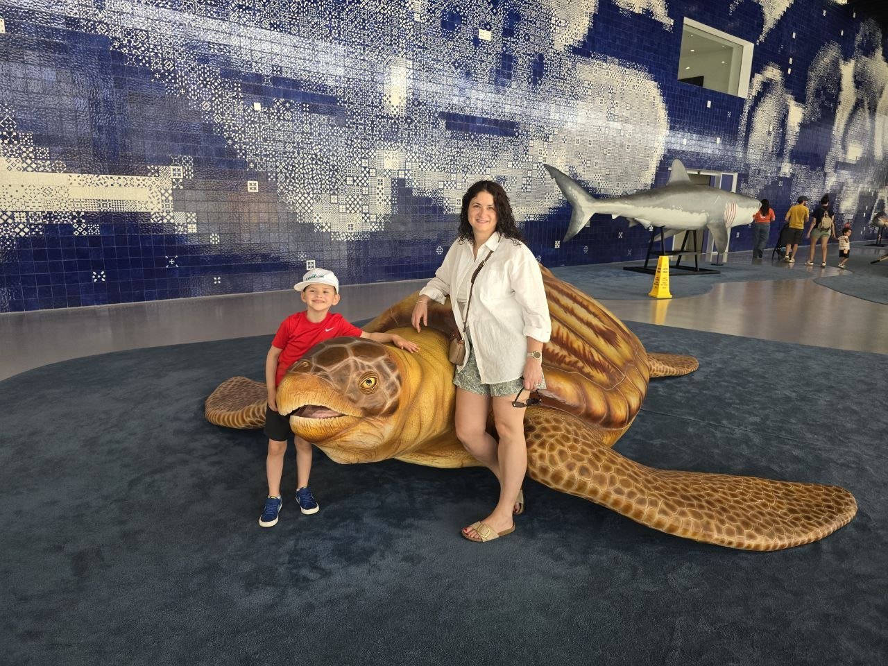Catherine and Noah posing beside a large sea turtle sculpture inside the Oceanário