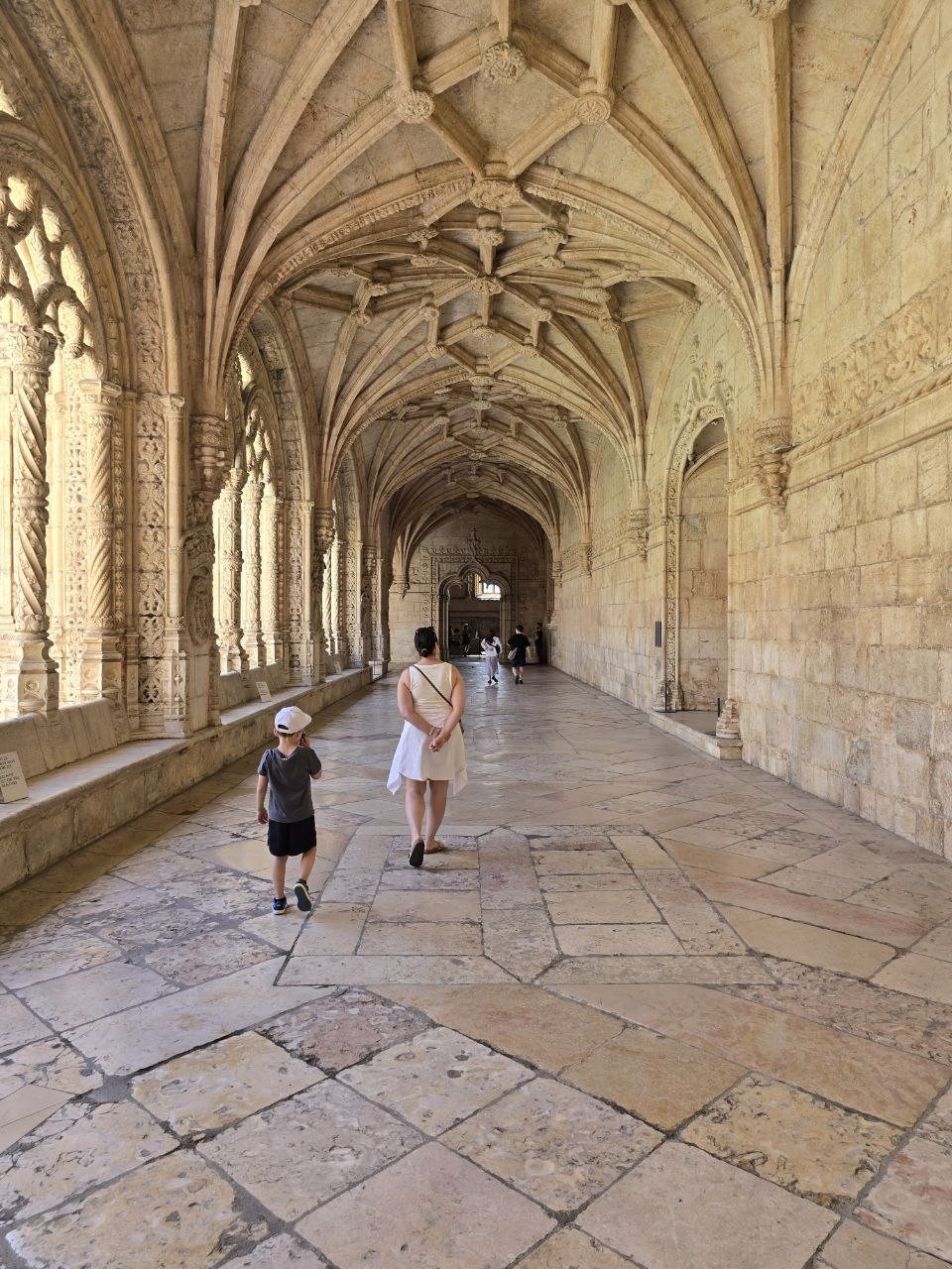 Family walking through a Jerónimos Monastery corridor