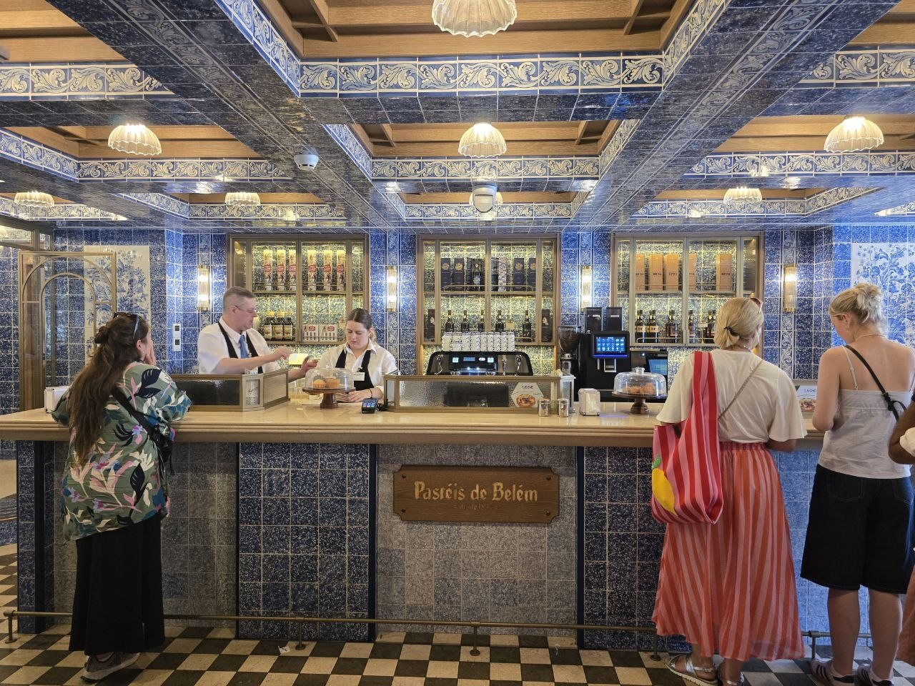 Busy Pastéis de Belém counter with pastries and staff