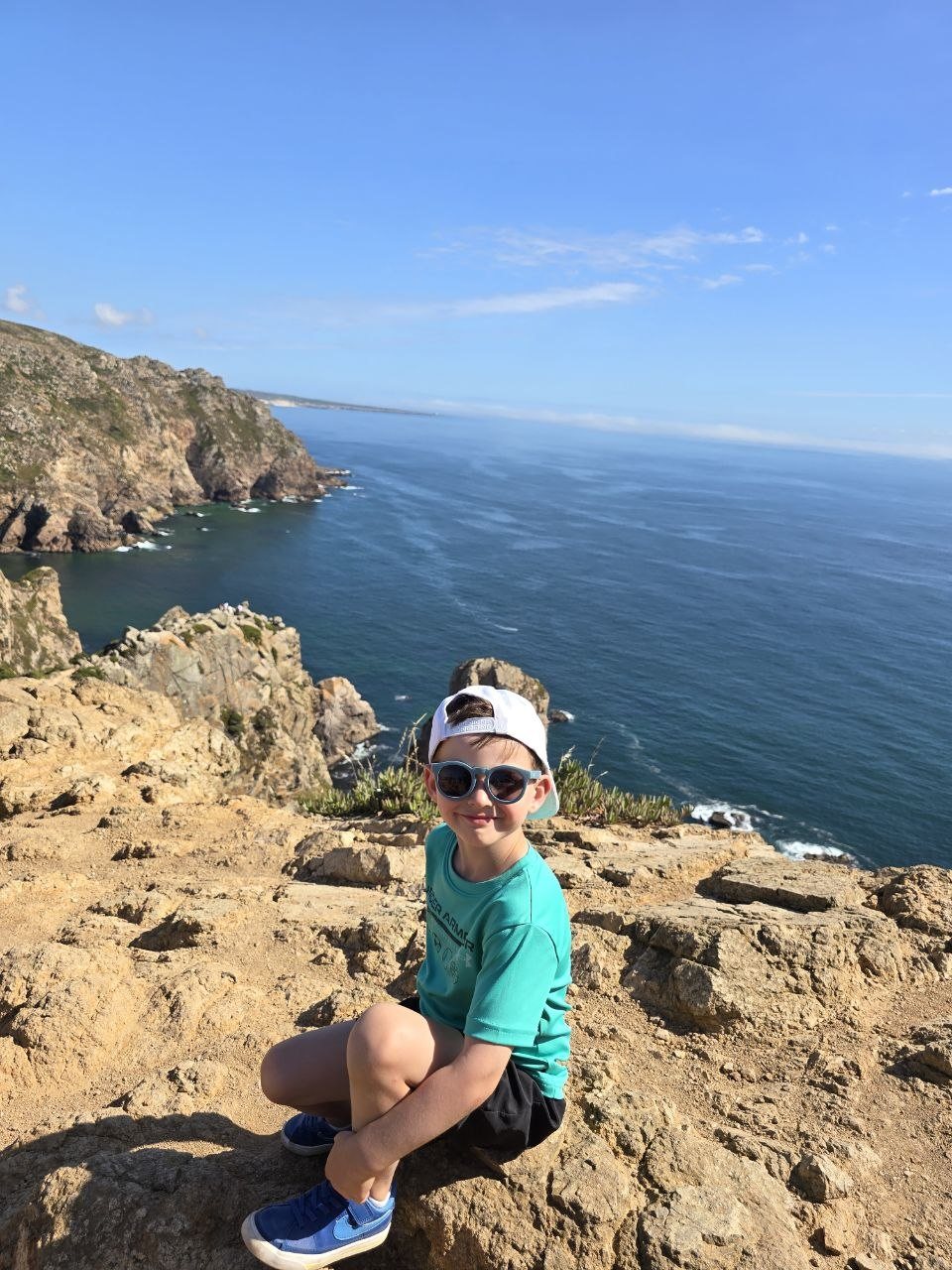 Noah sitting on rocks above the ocean cliffs
