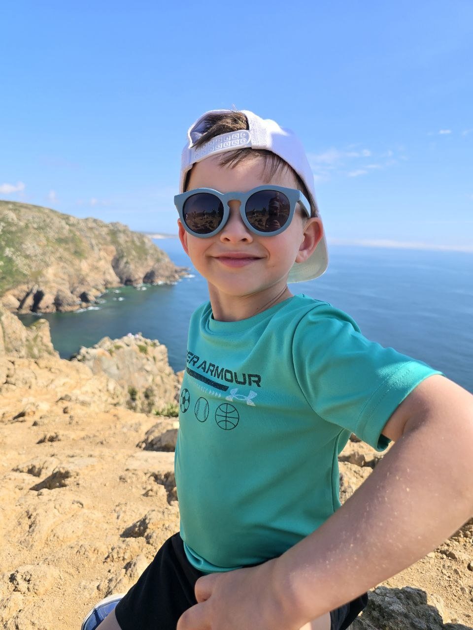 Noah wearing sunglasses at a cliffside coastal viewpoint