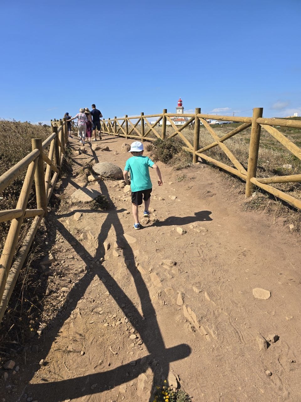 Noah walking along a fenced dirt path near the coastal viewpoint