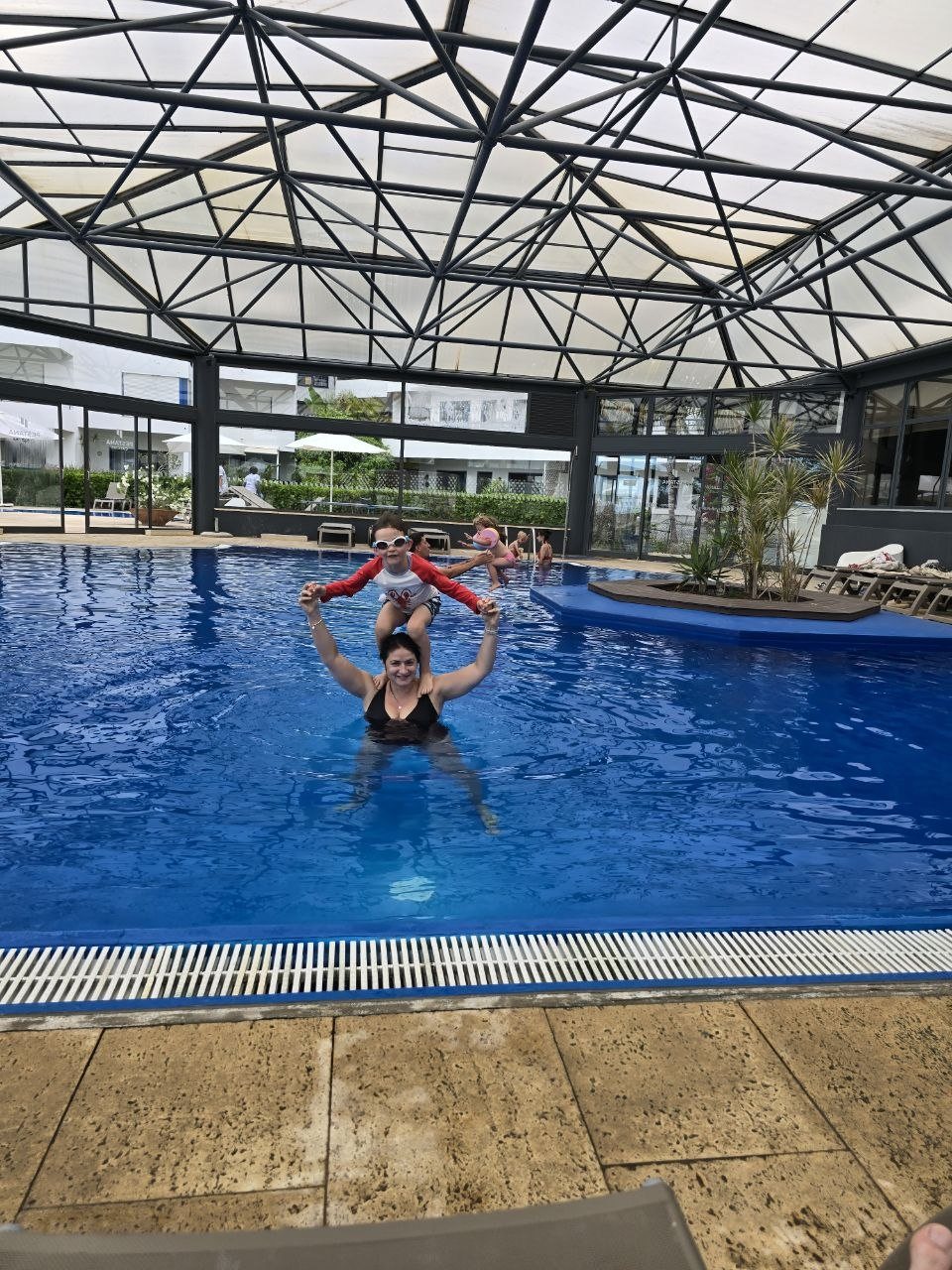 Noah standing on Catherine’s shoulders in the warm indoor pool at Pestana Cascais