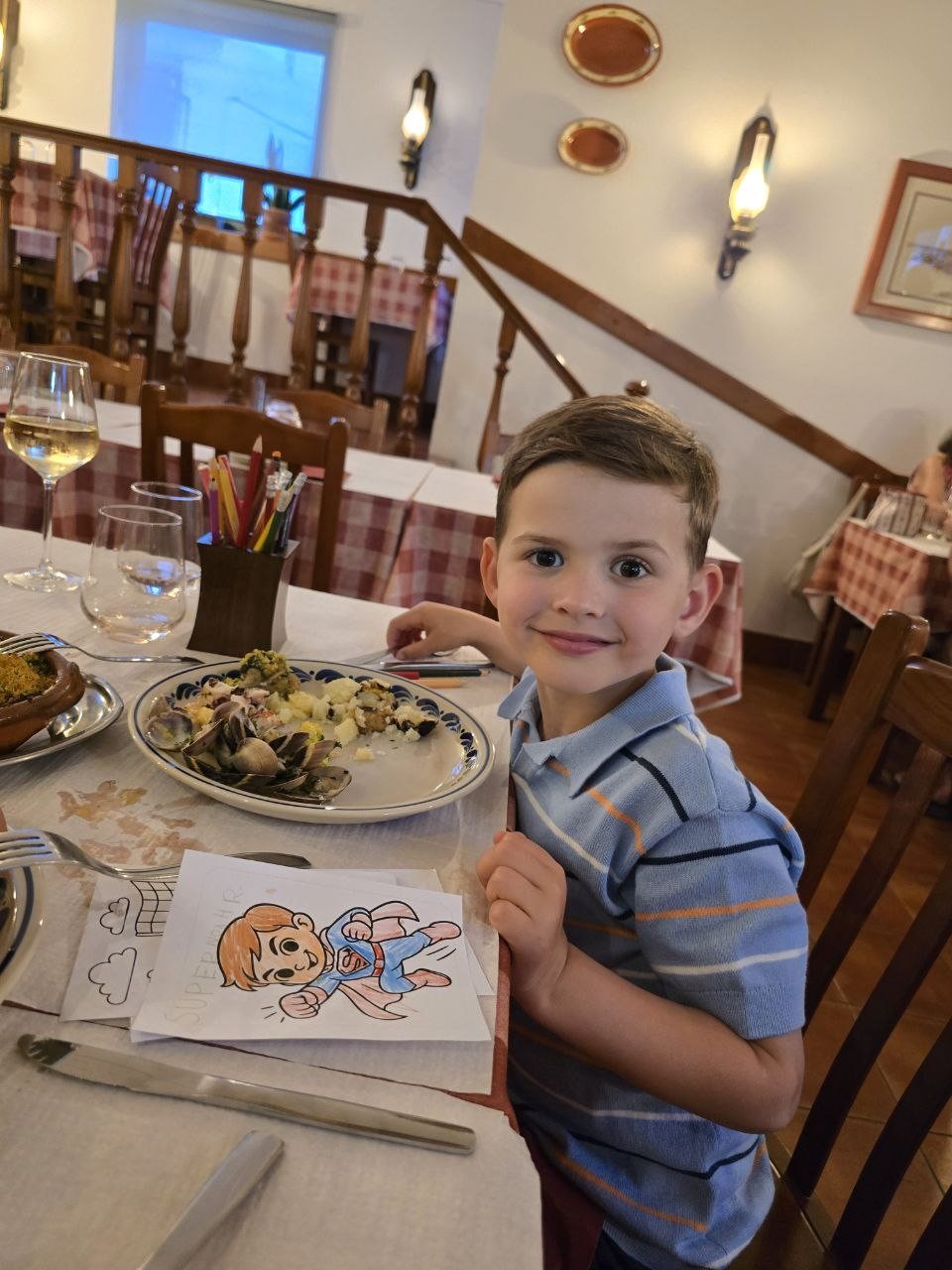 Noah smiling beside his plate and colouring page at Restaurant Pereira