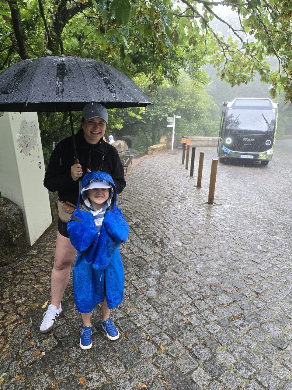 Noah and Catherine standing under umbrellas on a rainy cobblestone street