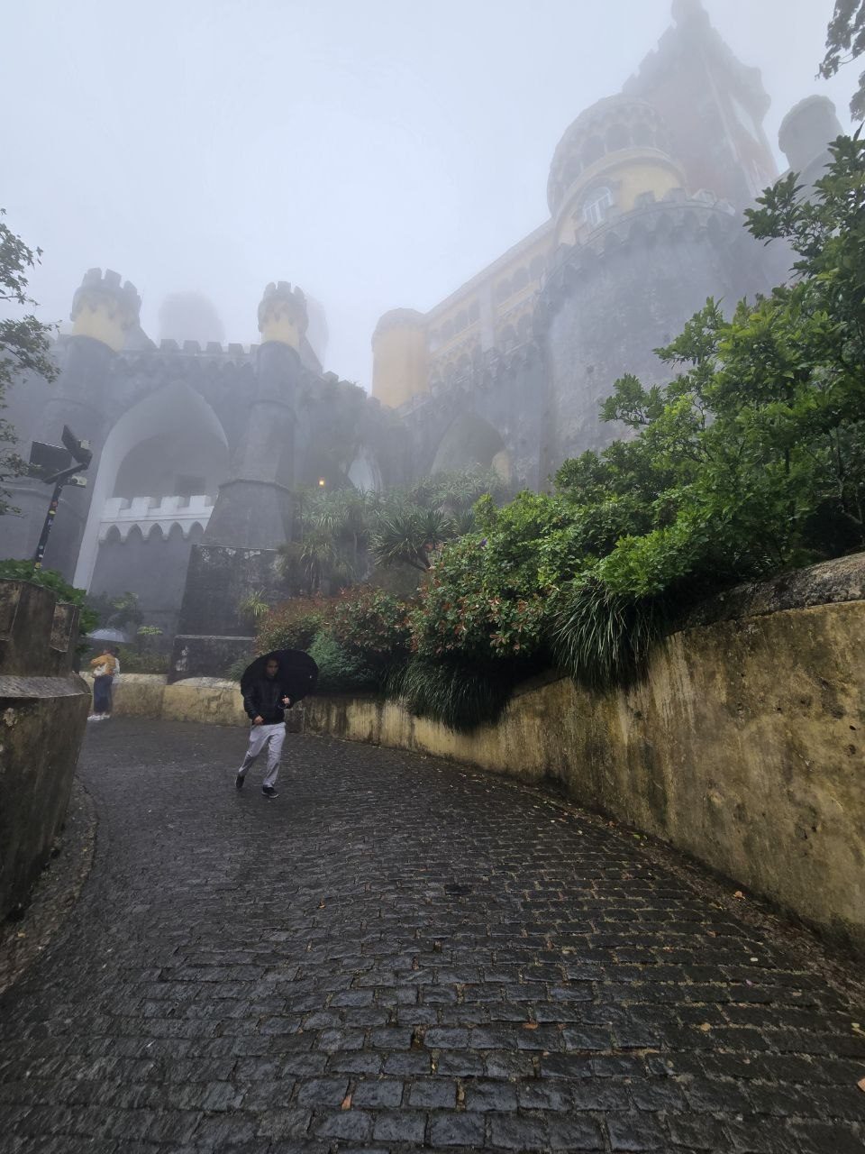 Foggy uphill cobblestone road leading toward Pena Palace