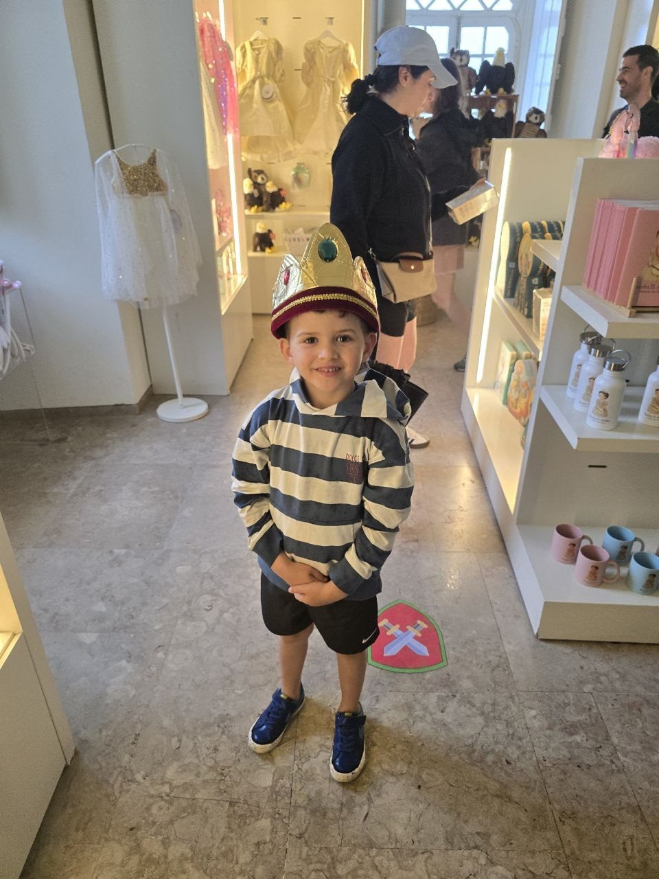 Noah standing inside a small shop wearing a striped shirt and cap