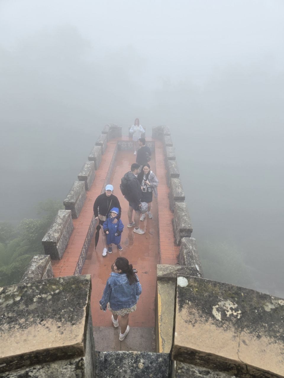 Foggy overhead view of a narrow red palace walkway with visitors