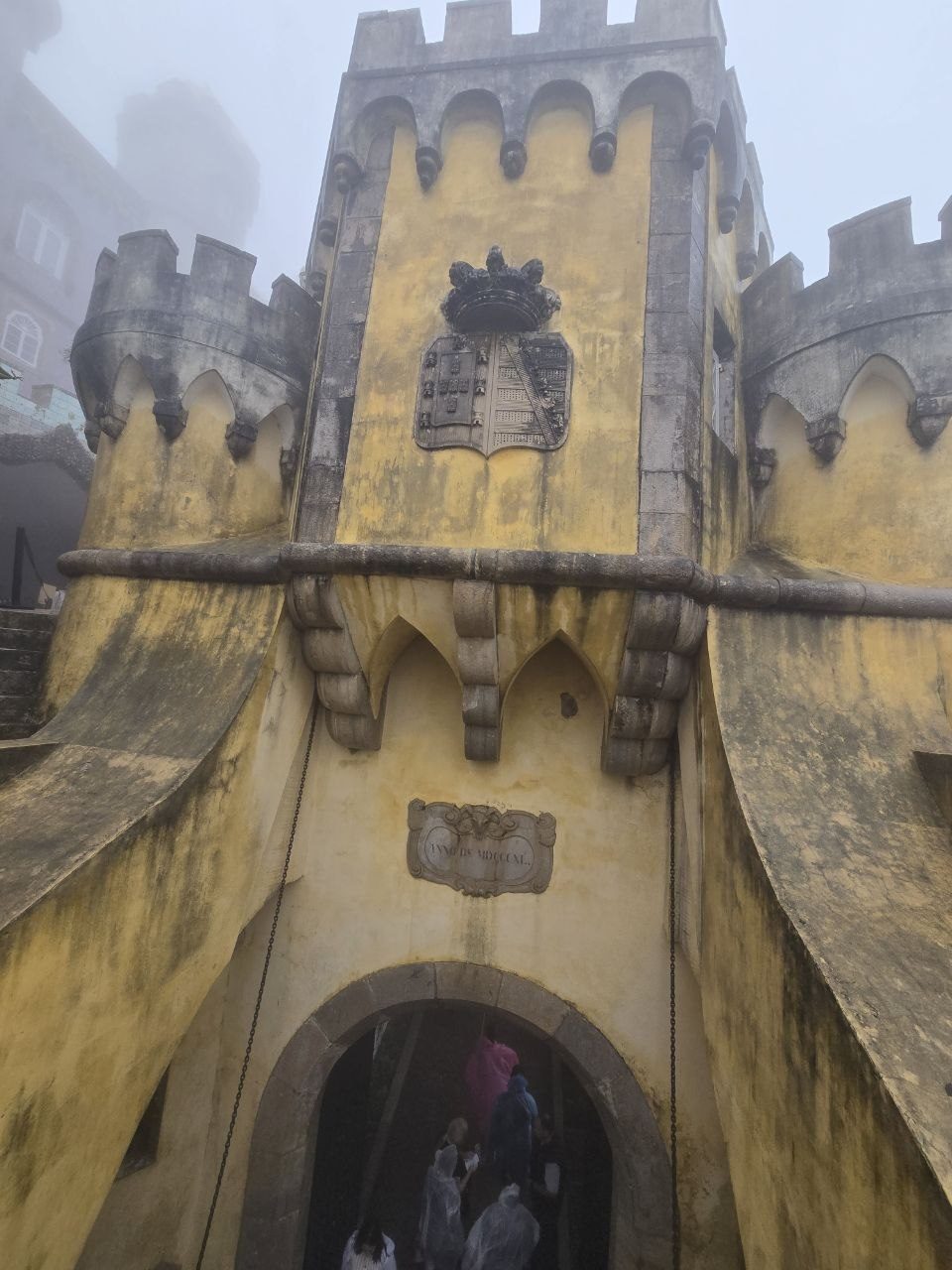 Yellow Pena Palace tower and arched doorway in fog