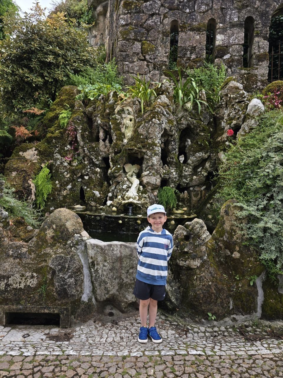 Noah standing beside a carved stone creature in a garden