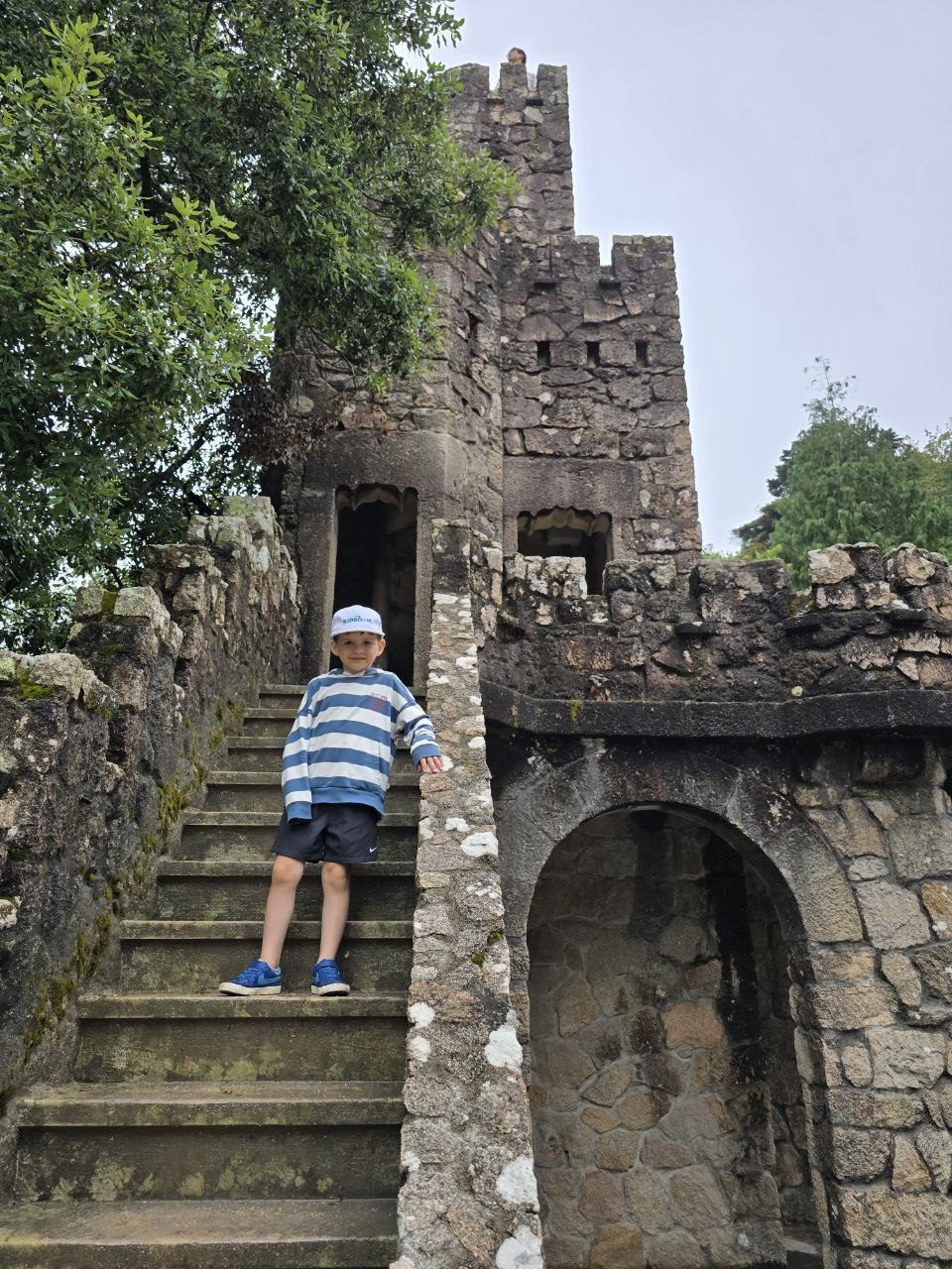 Noah climbing stone stairs beside a small castle-like tower