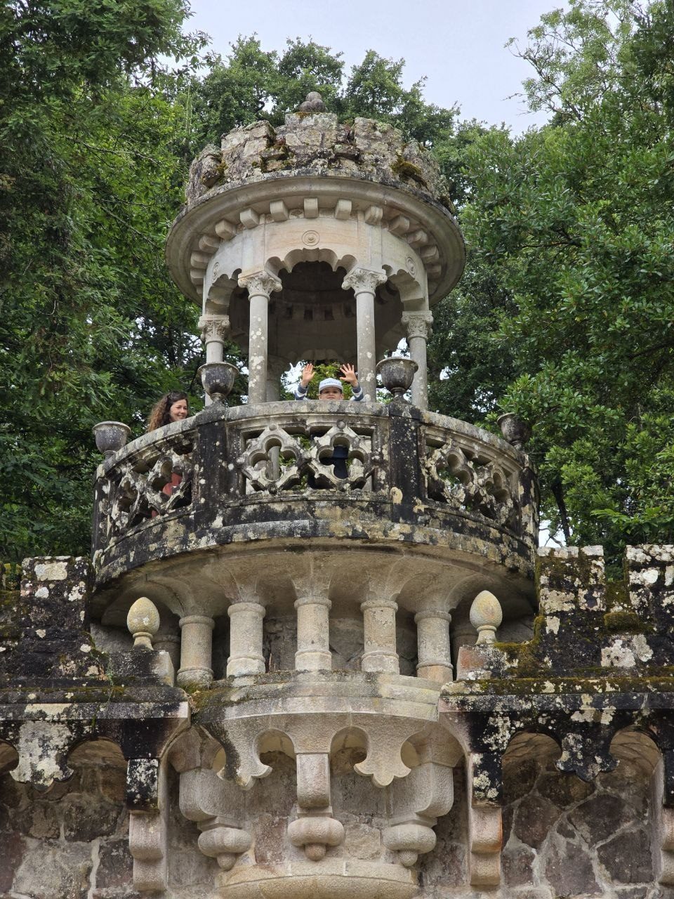 Ornate stone balcony tower surrounded by trees