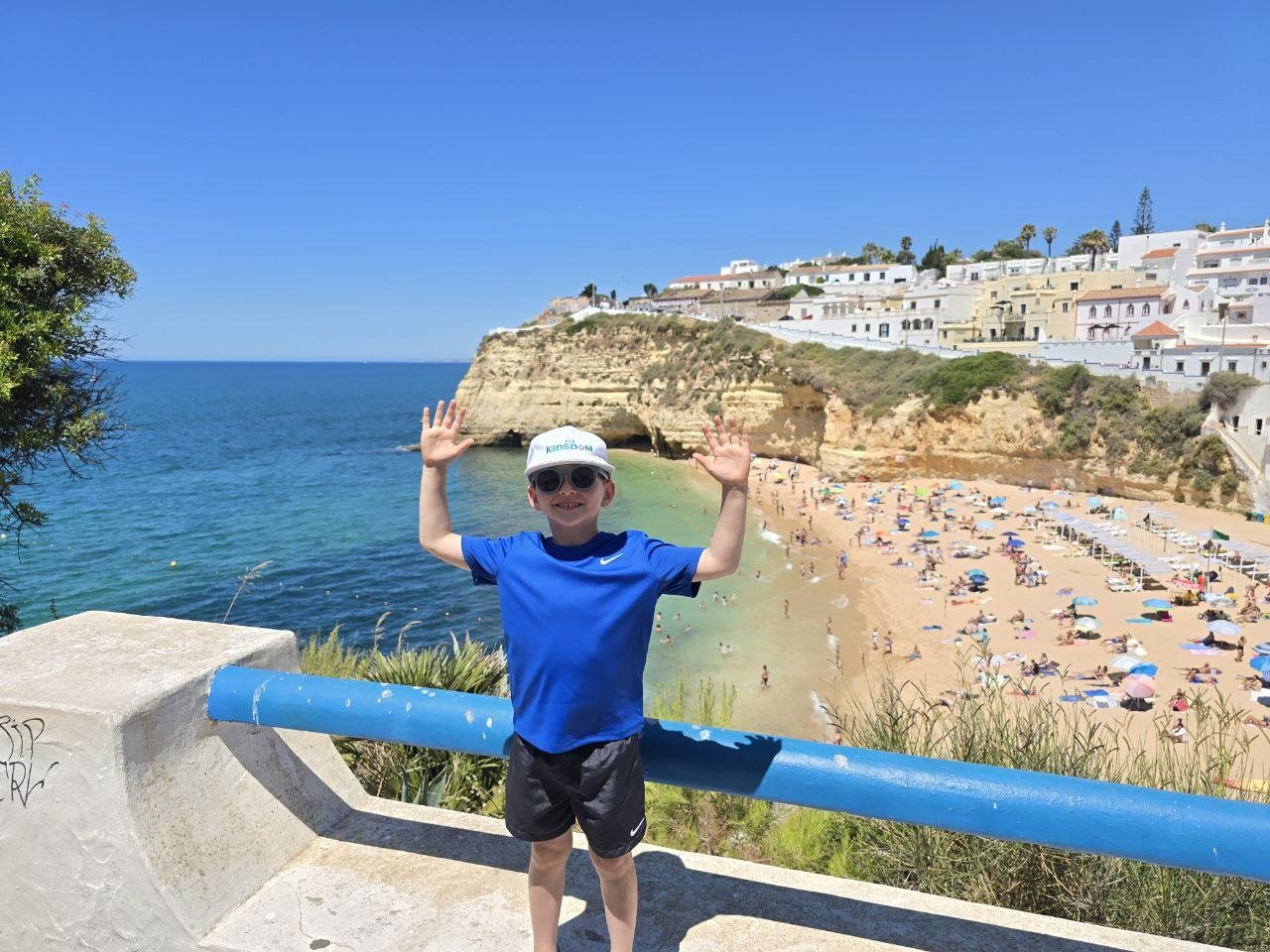 Noah posing at a blue railing above Carvoeiro beach
