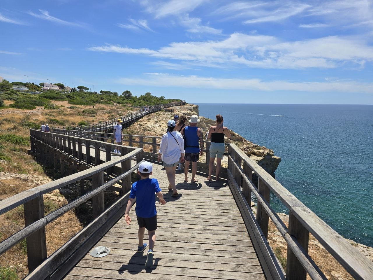 Family walking along the Carvoeiro boardwalk above the sea