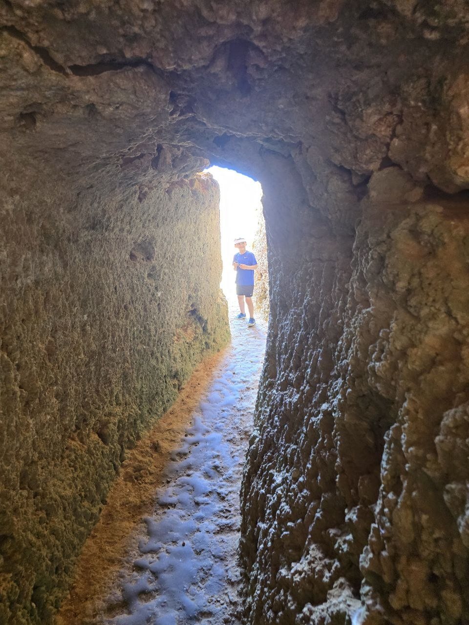 Narrow stone passage with bright daylight at the end