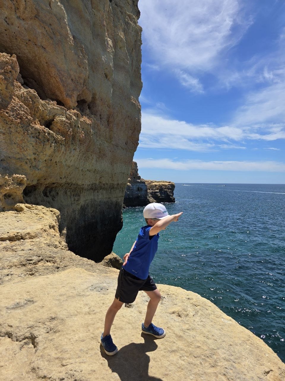 Noah posing near a cliff wall with the ocean behind him